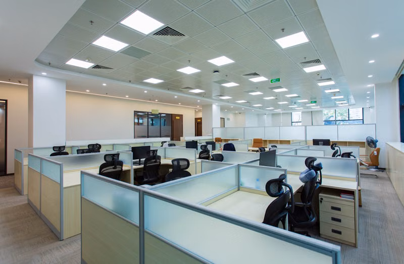 Commercial movers wrapping office desks and organizing workplace equipment for relocation